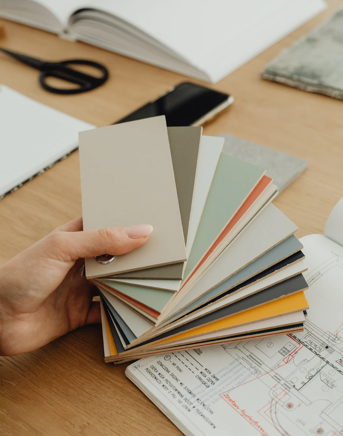 Hand holding colour swatches over a design layout